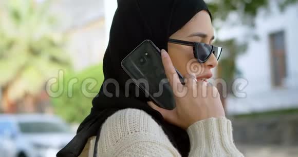 戴头巾的女人用手机说话视频的预览图