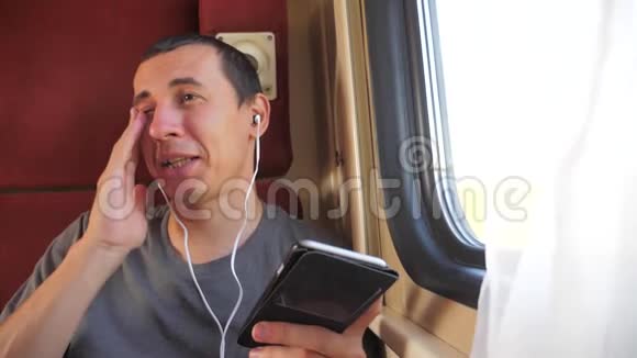 男子听着火车车厢车厢车厢里的音乐生活方式旅行慢动作视频一个男人视频的预览图