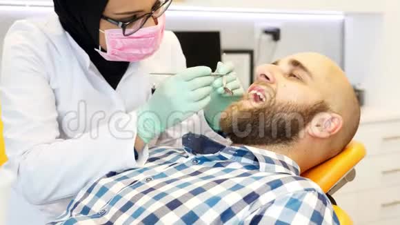 戴头巾的牙医检查病人的牙齿视频的预览图