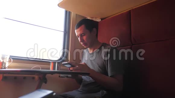 男人坐在火车车厢里拿着生活方式智能手机喝着咖啡和茶慢动作视频的预览图
