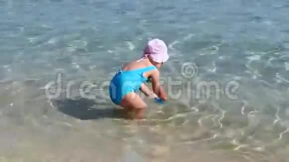 穿着蓝色泳衣在海滩上玩耍的小女孩视频的预览图