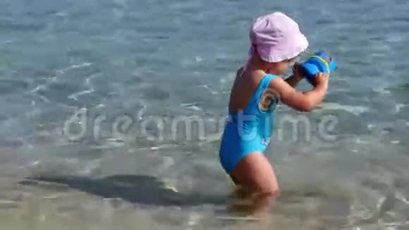 穿着蓝色泳衣在海滩上玩耍的小女孩视频的预览图