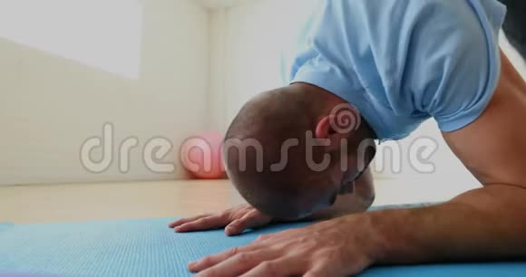 男子在健身室的垫子上锻炼视频的预览图