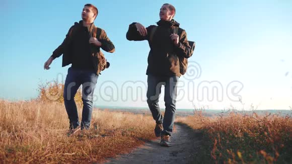 两个背着背包徒步旅行的人正沿着小路往山上爬慢动作视频视频的预览图