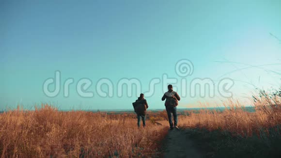 两个带着背包徒步旅行的男子正在沿着爬山的小路散步慢动作视频的预览图