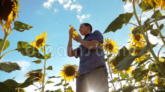 农夫手里拿着一个塑料瓶向日葵油立在田野里慢动作视频向日葵生活方式视频的预览图