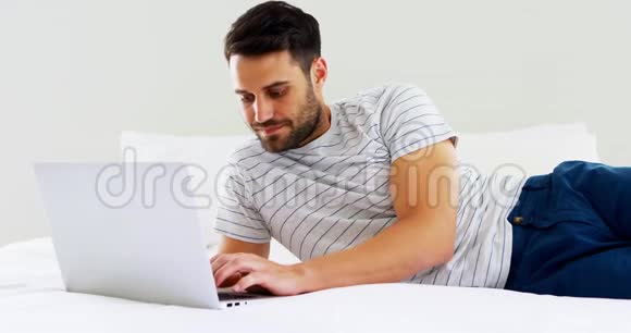 在卧室的床上使用笔记本电脑的男人视频的预览图