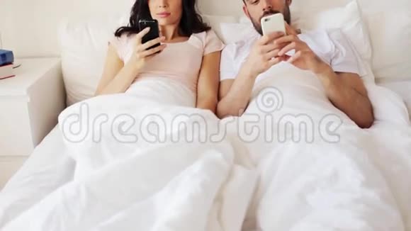 快乐的一对在床上有智能手机的夫妇视频的预览图