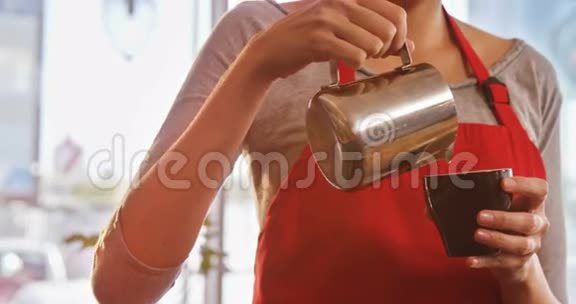 服务员在咖啡杯里倒牛奶同时准备咖啡视频的预览图