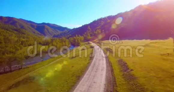 在阳光明媚的夏日早晨中气飞越新鲜的山河和草地农村土路下面视频的预览图