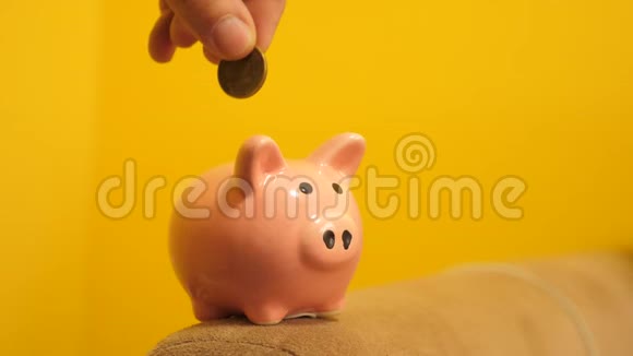猪银行的经营理念一只手把硬币放在黄色背景的生活方式上的储蓄罐里省钱就是视频的预览图