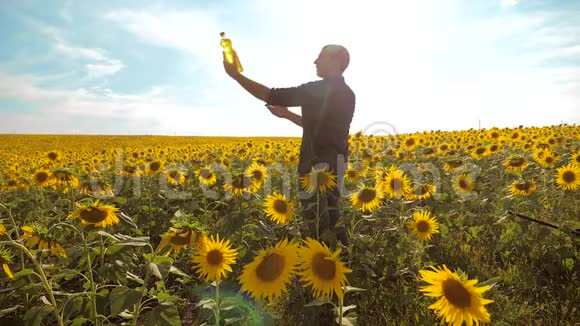 日落时分农夫手捧一瓶葵花籽油农民农业塑料瓶视频的预览图