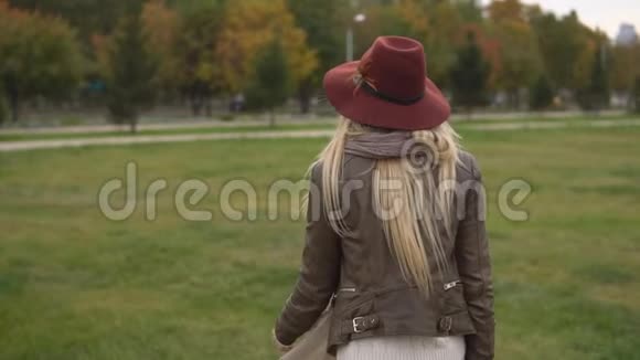 美丽的金发女孩在公园里散步视频的预览图
