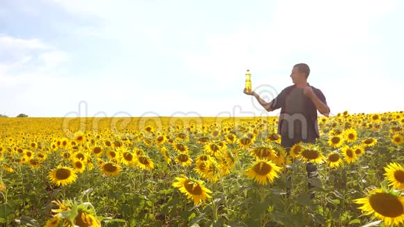 日落时分农夫手持一瓶葵花油在田野里葵花油生产的人秀视频的预览图