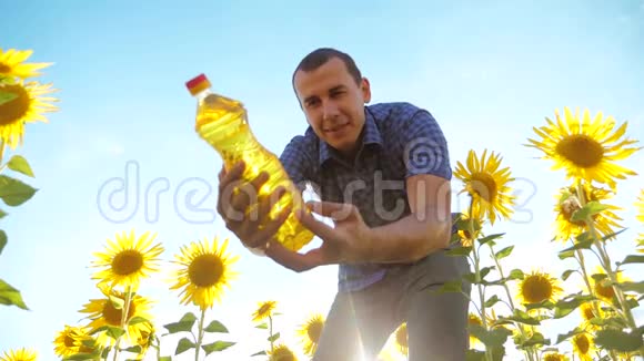 农夫手里拿着一个塑料瓶向日葵油站在田野里慢动作视频葵花籽油视频的预览图