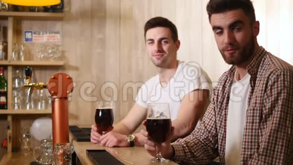 两个年轻人坐在酒吧里边喝啤酒边聊天视频的预览图