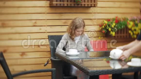 年轻女子用平板电脑和电话在咖啡馆喝茶视频的预览图