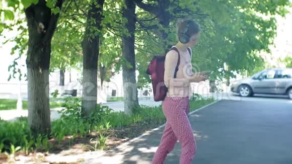年轻时尚的美女在城市街道上听音乐的大监控耳机视频的预览图