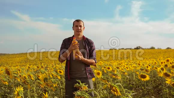 男人农夫手拿一瓶葵花油在生活日落的田野里慢动作视频人农农业视频的预览图