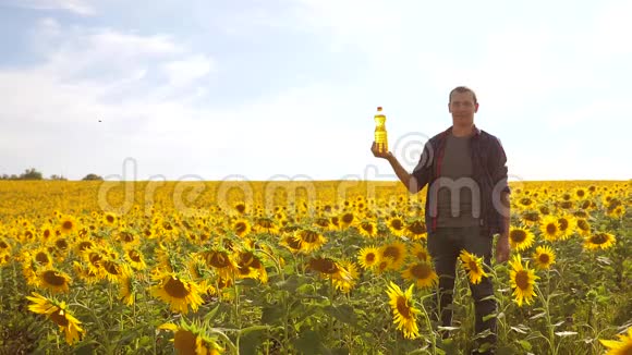 日落时分农夫手捧一瓶葵花籽油慢动作视频农民农业生活方式视频的预览图