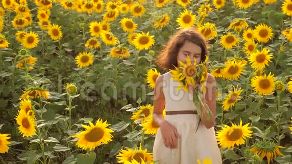 快乐的小女孩在向日葵地上过着夏天的生活向日葵里美丽的小女孩慢动作视频视频的预览图