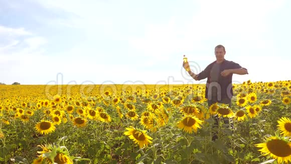 日落时分农夫手捧一瓶葵花籽油男人展示生活方式葵花籽油的生产视频的预览图