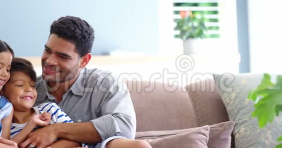 幸福的一家人坐在沙发上在客厅拥抱视频的预览图