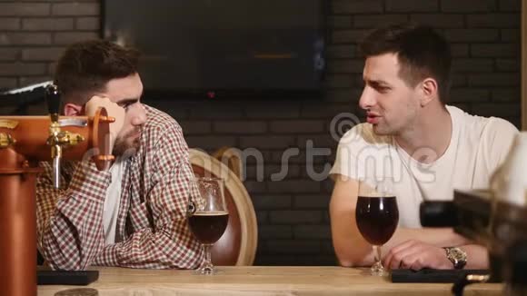 两个年轻人坐在酒吧里边喝啤酒边聊天视频的预览图