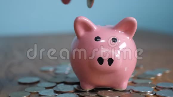 猪银行业务站在一堆硬币的概念上手是一种生活方式把硬币放在黄色的储蓄罐里视频的预览图