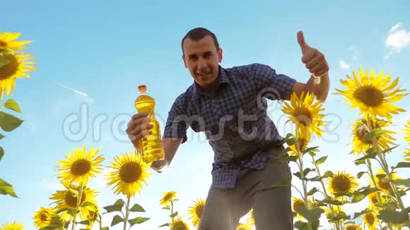 男人手里拿着一个塑料生活方式瓶葵花油站在田野里慢速视频视频的预览图