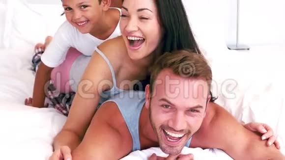 可爱的一家人在父母的床上玩耍视频的预览图