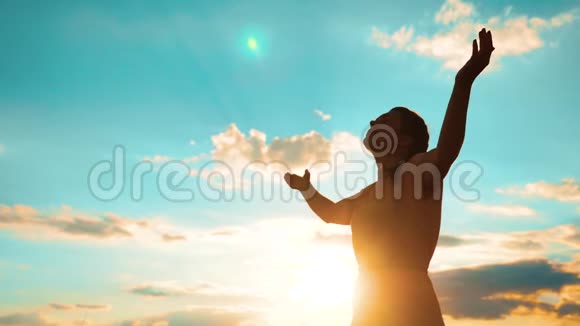 女人跪着祈祷女孩在生活方式日落时双手交叉祈祷剪影慢动作视频女孩视频的预览图