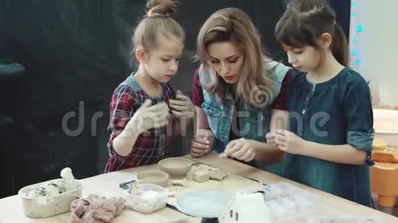 母亲和两个女儿在陶艺作坊的一个创意班孩子们用粘土做形状视频的预览图