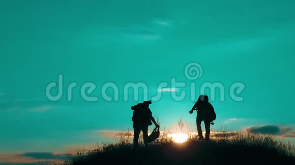 两个男子游客徒步旅行者剪影去山上日落旅游慢动作视频旅行者成功视频的预览图