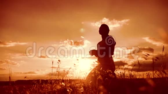 女人跪着祈祷女孩在日落时双手交叉祈祷剪影慢动作视频生活方式女孩视频的预览图