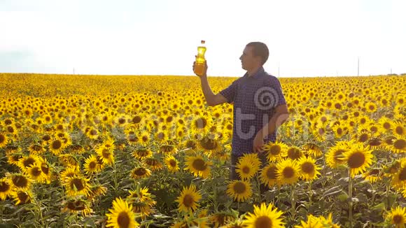 男子农民探索田野生活方式与向日葵慢动作视频男人的生活方式农民手拿瓶子视频的预览图