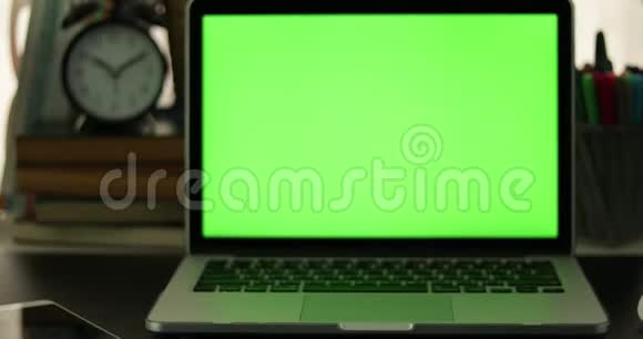 有绿色屏幕的笔记本电脑黑暗的办公室完美地放置你自己的图像或视频正在使用的技术绿色屏幕视频的预览图