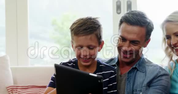 在客厅里使用数码平板电脑的幸福家庭视频的预览图