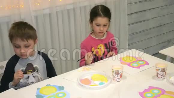 孩子们男孩和女孩在教室里围着桌子坐在一起画画视频的预览图