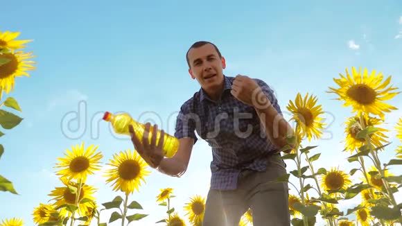农夫手里拿着一个塑料瓶向日葵油站在田野里生活方式慢视频视频的预览图