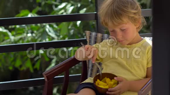 小可爱的男孩在露台上吃芒果视频的预览图