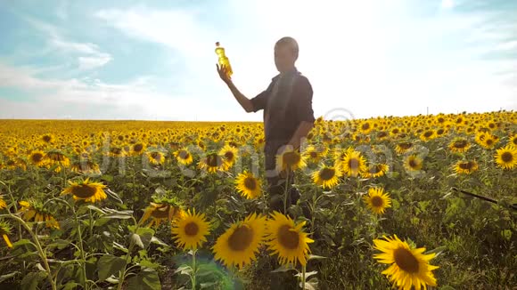 日落时分农夫手里拿着一瓶向日葵的生活方式给田野加油农民农业塑料瓶视频的预览图