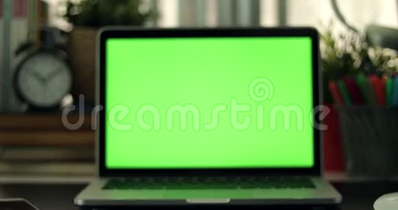 有绿色屏幕的笔记本电脑黑暗的办公室完美地放置你自己的图像或视频正在使用的技术绿色屏幕视频的预览图
