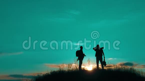 两个男子游客徒步旅行者剪影去山生活方式日落旅游慢动作视频旅行者成功视频的预览图