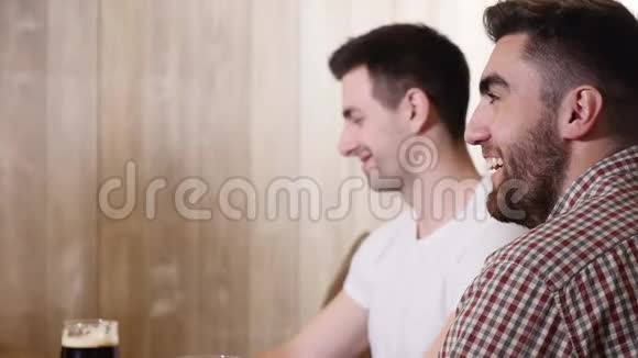 两个年轻人的朋友坐在酒吧里互相交谈一边喝啤酒视频的预览图