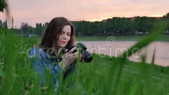 在刮风的天气里美丽的女游客用专业的照相机在河岸上拍照视频的预览图