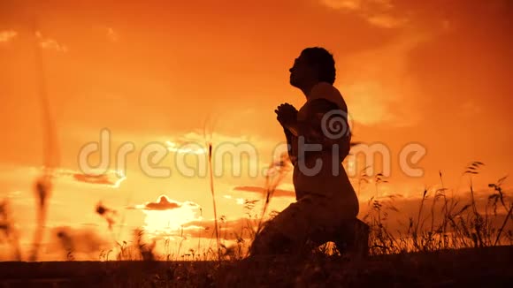 女孩祈祷女孩在日落时双手交叉祈祷剪影慢动作视频女孩双手交叉祈祷视频的预览图