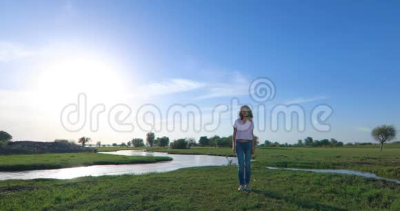 绿茵草地上有一条河的年轻女子视频的预览图