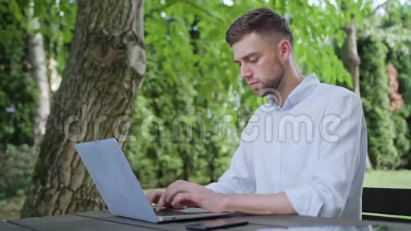 一个年轻人在公园里用笔记本电脑视频的预览图