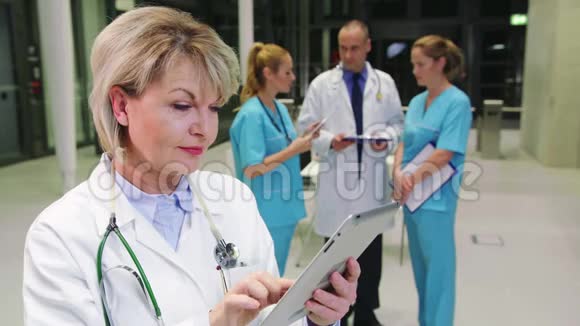 医院走廊用数码平板电脑微笑女医生视频的预览图